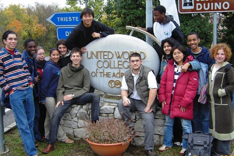 Multi ethic group of students posing for a photo around the UWC Adriatic sign in Duino